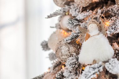 A Christmas angel on the branches of a Christmas tree against the background of a clock showing 12. New Year's Eve 2022 Celebration