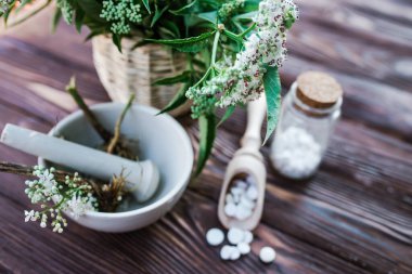 Valerian tablets with sedative properties. Pharmaceutical jar with pills on a wooden table. Cooking Valerian Root in a Mortar for Herbalism Elixirs. Soft focus