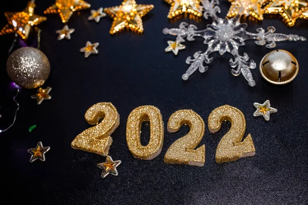 Happy New Year 2022. Holiday background with golden Christmas decorations . 2022 numbers with gold jewelry balls and garland in form of stars.