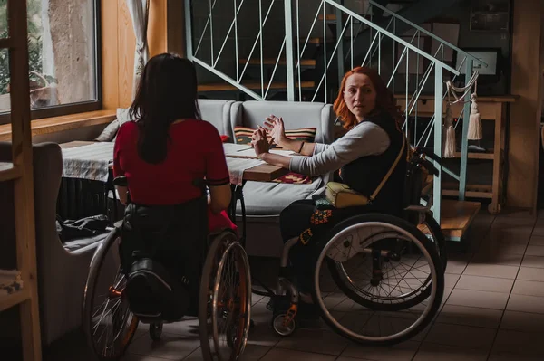 Two girls in wheelchairs in a cozy cafe waiting for an order. Accessible common areas for people with disabilities. Girls in wheelchairs on vacation while traveling