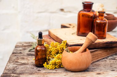 Immortelle, Curry Plant, Herb of St. John, Immortelle ve botanik olarak, Helichrysum arenyumu. Gereken yağ için boş cam eczane şişelerinin yanında. Doğal kozmetik ve güzellik konsepti