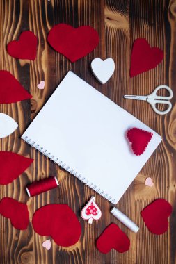 Empty notepad on spring on wooden table. Hand-sewn red hearts. Letter to Valentine's Day concept. Congratulations with Valentine.