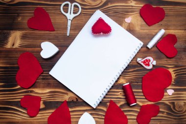 Empty notepad on spring on wooden table. Hand-sewn red hearts. Letter to Valentine's Day concept. Congratulations with Valentine.