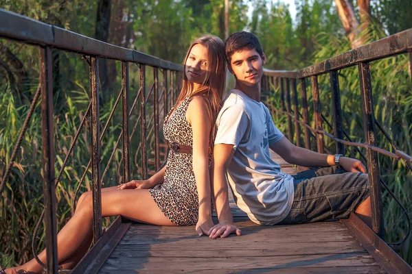 Casal Apaixonado Senta Uma Ponte Madeira Com Grades Enferrujadas Costas — Fotografia de Stock