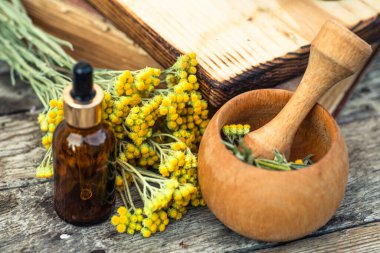 Immortelle, Curry Plant, Herb of St. John, Immortelle ve botanik olarak, Helichrysum arenyumu. Gereken yağ için boş cam eczane şişelerinin yanında. Doğal kozmetik ve güzellik konsepti