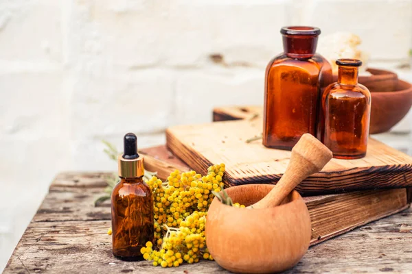 Immortelle, Curry Plant, Herb of St. John, Immortelle ve botanik olarak, Helichrysum arenyumu. Gereken yağ için boş cam eczane şişelerinin yanında. Doğal kozmetik ve güzellik konsepti
