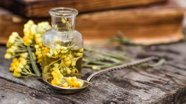 Bir kaşıkta Temmuz arenyumu, helichrysum arenaryumu, cüce sonsuzluğu, ölümsüzlük, köri bitkisi, İtalyan saman çiçeği eczane şişeleri tentür ve güzellik salonları ve alternatif tıp için gerekli yağlar