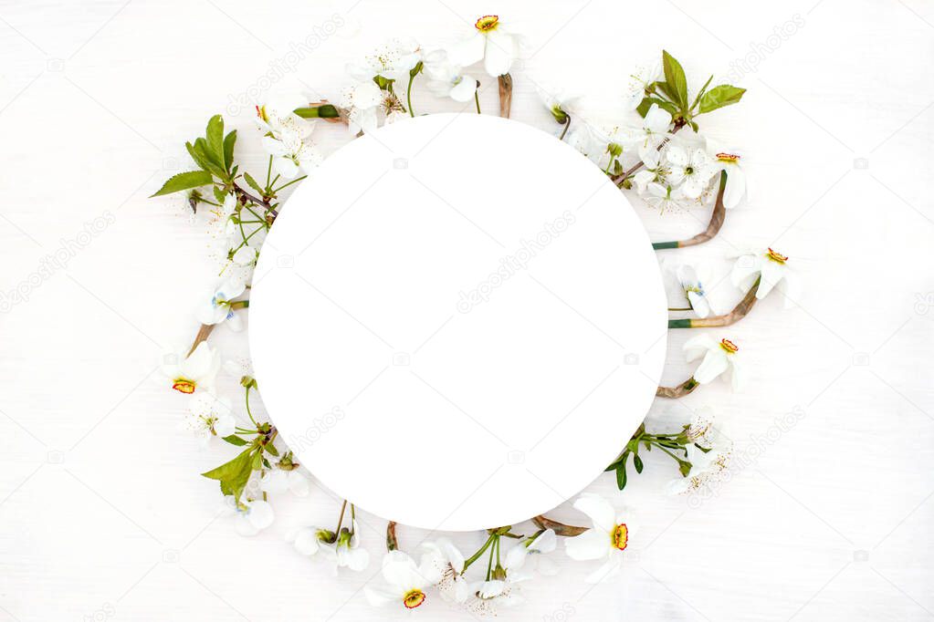 Round frame with spring flowers. fresh cherry blossoms, violets and white daffodils in the form of wreath on wooden background.