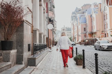 Eski cadde boyunca kaldırım boyunca yürüyen yaşlı bir kadının dikiz manzarası, sabahın erken saatlerinde şehrin turistik kesiminde kaldırım taşları ile özgürlük ve rahatlığın tadını çıkarıyor. Aktif kıdemli kadın güneşli bir günde dinleniyor..