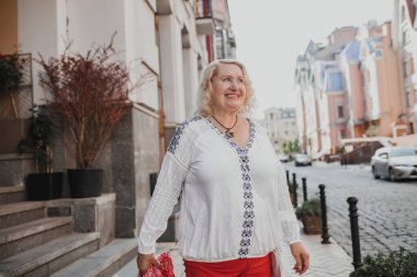 Sonbaharda şehir caddesinde yürüyen mutlu olgun bir kadının portresi. Sarışın, güzel bir kadın emekliliğinde yürüyüşe çıkar.