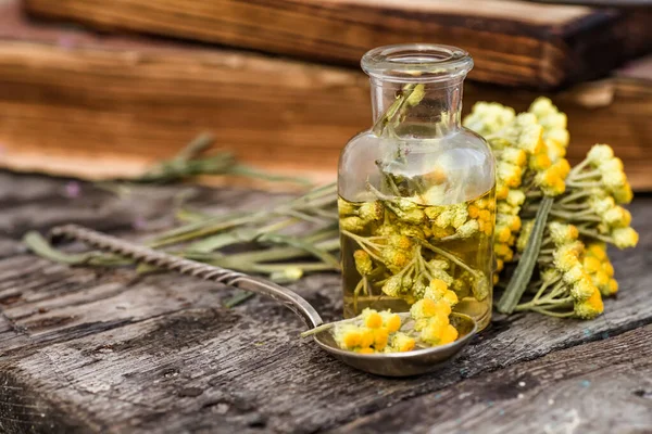 Bir kaşıkta Temmuz arenyumu, helichrysum arenaryumu, cüce sonsuzluğu, ölümsüzlük, köri bitkisi, İtalyan saman çiçeği eczane şişeleri tentür ve güzellik salonları ve alternatif tıp için gerekli yağlar