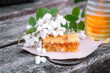 Kırsal ahşap arka planda akasya çiçekleri olan kavanozdaki bal. Altın, taze.