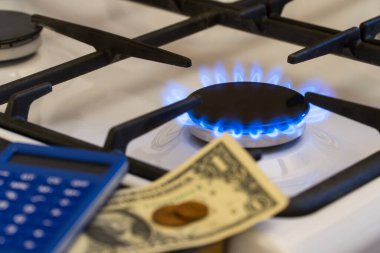 Eksiklik ve gaz krizi. Yanan bir gaz sobasının arka planında para ve hesap makinesi