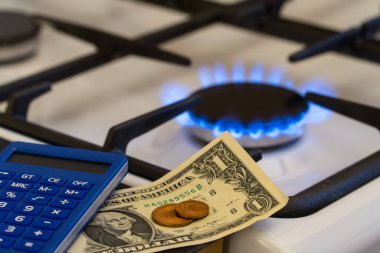 Eksiklik ve gaz krizi. Yanan bir gaz sobasının arka planında para ve hesap makinesi