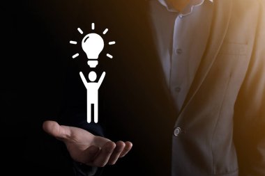 İş adamı elinde ampullü bir ikon tutuyor, yenilikçi teknoloji ve yaratıcılıkla yeni fikirler üretiyor. Işıldayan ampullerle yaratıcılık kavramı