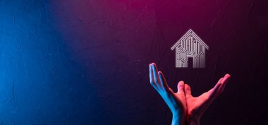 İş adamı ev ikonunu tutuyor. Marketin ev kontrollü, akıllı ev ve ev otomasyon uygulaması konsepti. PCB tasarımı ve akıllı telefonu olan kişi. Yenilik teknolojisi internet ağı kavramı