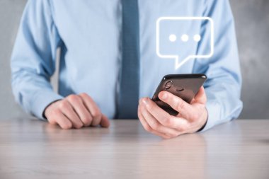 Elinde mesaj ikonu tutan bir iş adamı, elinde baloncuklu konuşma tebligat işareti var. Sohbet simgesi, SMS simgesi, yorum simgesi, konuşma baloncukları.
