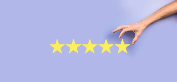 Man holds smart phone in hands and gives positive rating, icon five star symbol to increase rating of company concept on blue background.Customer service experience and business satisfaction survey