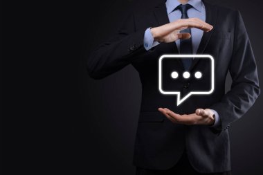 Elinde mesaj ikonu tutan bir iş adamı, elinde baloncuklu konuşma tebligat işareti var. Sohbet simgesi, SMS simgesi, yorum simgesi, konuşma baloncukları.