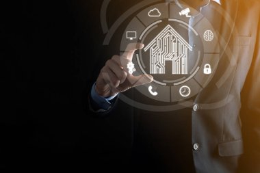 İş adamı ev ikonunu tutuyor. Marketin ev kontrollü, akıllı ev ve ev otomasyon uygulaması konsepti. PCB tasarımı ve akıllı telefonu olan kişi. Yenilik teknolojisi internet ağı kavramı