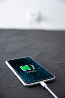 Beyaz arka planda kablosuz şarj cihazında cep telefonu var. Güç kaynağına bağlı akıllı telefonlar. Düşük pil seviyesi sorunları. Fişe takıldı