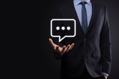 Elinde mesaj ikonu tutan bir iş adamı, elinde baloncuklu konuşma tebligat işareti var. Sohbet simgesi, SMS simgesi, yorum simgesi, konuşma baloncukları.