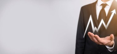 İş adamı artan ekran grafiği, pozitif büyüme ikonu okları üzerinde duruyor. Yaratıcı iş grafiğine yükselen oklarla işaret ediyor. Finansal, ticari büyüme kavramı.