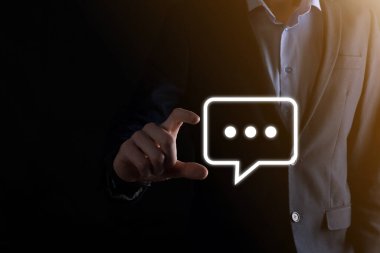 Elinde mesaj ikonu tutan bir iş adamı, elinde baloncuklu konuşma tebligat işareti var. Sohbet simgesi, SMS simgesi, yorum simgesi, konuşma baloncukları.