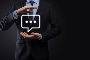 Elinde mesaj ikonu tutan bir iş adamı, elinde baloncuklu konuşma tebligat işareti var. Sohbet simgesi, SMS simgesi, yorum simgesi, konuşma baloncukları.