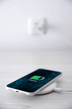 Beyaz arka planda kablosuz şarj cihazında cep telefonu var. Güç kaynağına bağlı akıllı telefonlar. Düşük pil seviyesi sorunları. Fişe takıldı