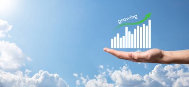 Holografik grafikler ve borsa istatistikleri tutan işadamı kâr elde ediyor. Büyüme planlama ve iş stratejisi kavramı. İyi ekonomi formunun dijital ekran görüntüsü.