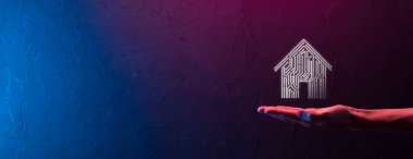 İş adamı ev ikonunu tutuyor. Marketin ev kontrollü, akıllı ev ve ev otomasyon uygulaması konsepti. PCB tasarımı ve akıllı telefonu olan kişi. Yenilik teknolojisi internet ağı kavramı