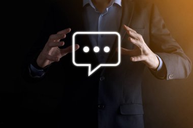 Elinde mesaj ikonu tutan bir iş adamı, elinde baloncuklu konuşma tebligat işareti var. Sohbet simgesi, SMS simgesi, yorum simgesi, konuşma baloncukları.