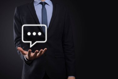Elinde mesaj ikonu tutan bir iş adamı, elinde baloncuklu konuşma tebligat işareti var. Sohbet simgesi, SMS simgesi, yorum simgesi, konuşma baloncukları.