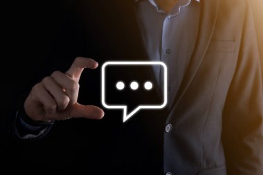 Elinde mesaj ikonu tutan bir iş adamı, elinde baloncuklu konuşma tebligat işareti var. Sohbet simgesi, SMS simgesi, yorum simgesi, konuşma baloncukları.