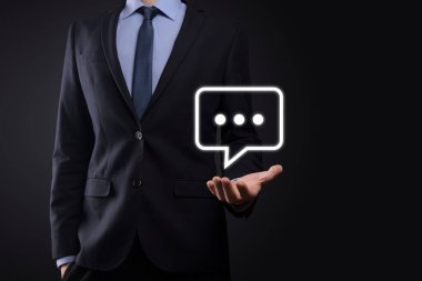 Elinde mesaj ikonu tutan bir iş adamı, elinde baloncuklu konuşma tebligat işareti var. Sohbet simgesi, SMS simgesi, yorum simgesi, konuşma baloncukları.