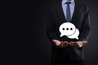 Elinde mesaj ikonu tutan bir iş adamı, elinde baloncuklu konuşma tebligat işareti var. Sohbet simgesi, SMS simgesi, yorum simgesi, konuşma baloncukları.