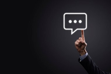 Elinde mesaj ikonu tutan bir iş adamı, elinde baloncuklu konuşma tebligat işareti var. Sohbet simgesi, SMS simgesi, yorum simgesi, konuşma baloncukları.