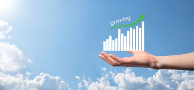 Holografik grafikler ve borsa istatistikleri tutan işadamı kâr elde ediyor. Büyüme planlama ve iş stratejisi kavramı. İyi ekonomi formunun dijital ekran görüntüsü.