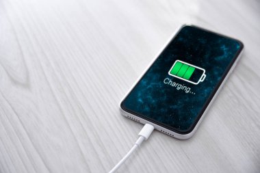 Beyaz arka planda kablosuz şarj cihazında cep telefonu var. Güç kaynağına bağlı akıllı telefonlar. Düşük pil seviyesi sorunları. Fişe takıldı