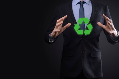 Takım elbiseli bir işadamı elinde bir geri dönüşüm simgesi tutuyor. Ekoloji, çevre ve koruma kavramı. Neon kırmızı mavi ışık.