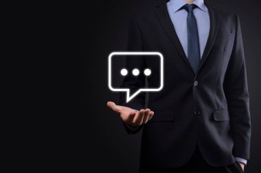 Elinde mesaj ikonu tutan bir iş adamı, elinde baloncuklu konuşma tebligat işareti var. Sohbet simgesi, SMS simgesi, yorum simgesi, konuşma baloncukları.