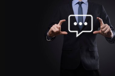 Elinde mesaj ikonu tutan bir iş adamı, elinde baloncuklu konuşma tebligat işareti var. Sohbet simgesi, SMS simgesi, yorum simgesi, konuşma baloncukları.