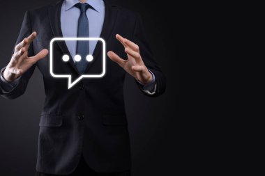 Elinde mesaj ikonu tutan bir iş adamı, elinde baloncuklu konuşma tebligat işareti var. Sohbet simgesi, SMS simgesi, yorum simgesi, konuşma baloncukları.