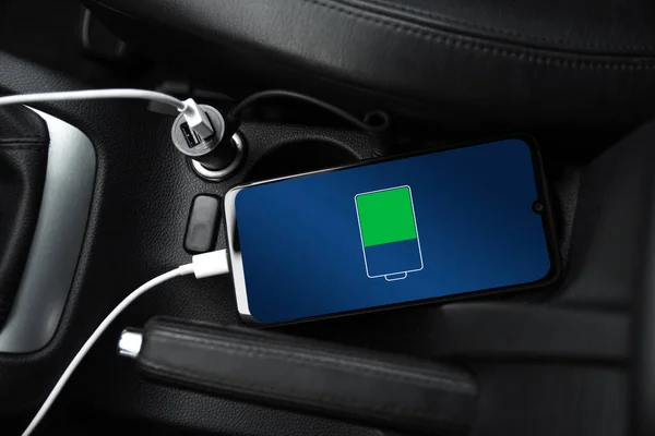 Cep telefonu, akıllı telefon, cep telefonu şarj edildi. Arabanın içinde USB şarj cihazıyla şarj edildi. modern siyah araba iç tasarımı.