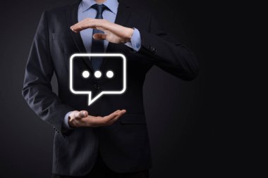 Elinde mesaj ikonu tutan bir iş adamı, elinde baloncuklu konuşma tebligat işareti var. Sohbet simgesi, SMS simgesi, yorum simgesi, konuşma baloncukları.