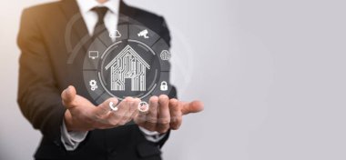 İş adamı ev ikonunu tutuyor. Marketin ev kontrollü, akıllı ev ve ev otomasyon uygulaması konsepti. PCB tasarımı ve akıllı telefonu olan kişi. Yenilik teknolojisi internet ağı kavramı