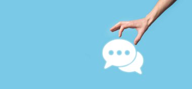 Elinde mesaj ikonu tutan bir iş adamı, elinde baloncuklu konuşma tebligat işareti var. Sohbet simgesi, SMS simgesi, yorum simgesi, konuşma baloncukları.