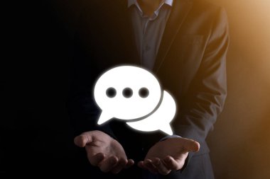 Elinde mesaj ikonu tutan bir iş adamı, elinde baloncuklu konuşma tebligat işareti var. Sohbet simgesi, SMS simgesi, yorum simgesi, konuşma baloncukları.