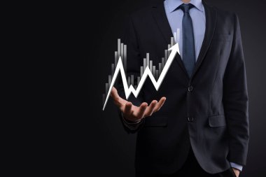 İş adamı satış verilerini ve ekonomik büyüme grafiğini elinde tutuyor. İş planlama ve strateji. Takas ticareti analiz ediliyor. Finansal ve bankacılık. Teknoloji dijital pazarlama. Kâr ve büyüyen plan.